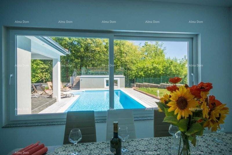 Essbereich mit großem Fenster und direktem Blick auf den Außenpool und die grüne Umgebung.