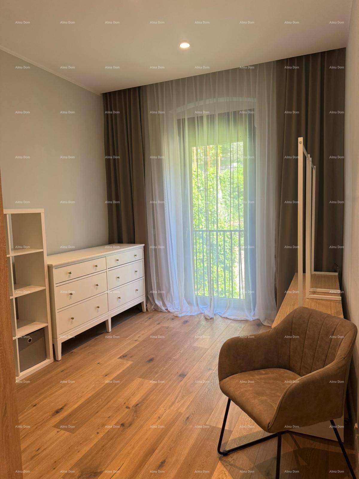 Helles Zimmer mit Holzboden, großem Fenster und modernen Möbeln, ideal als Schlaf- oder Gästezimmer.