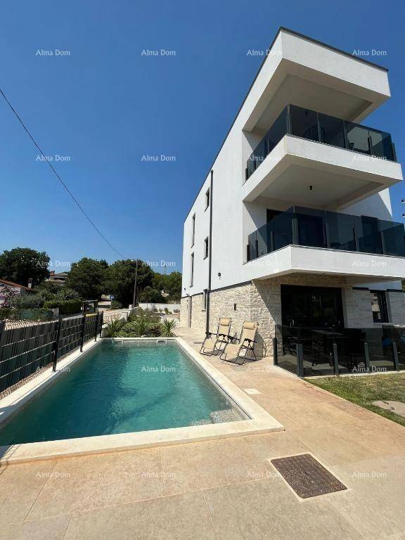 Neubau mit Pool und gepflasterter Terrasse, umgeben von Grünflächen.