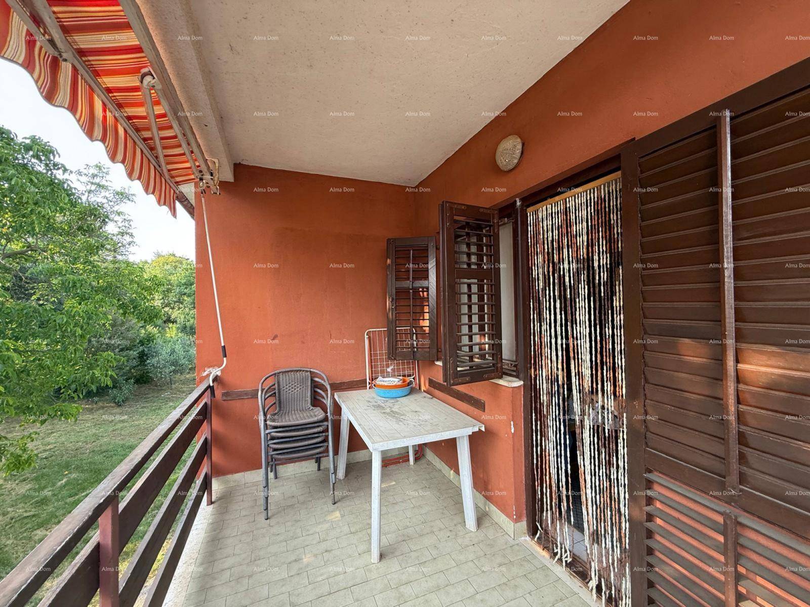 Gemütlicher Balkon mit Markise, kleinem Tisch und Stühlen, umgeben von Grün.