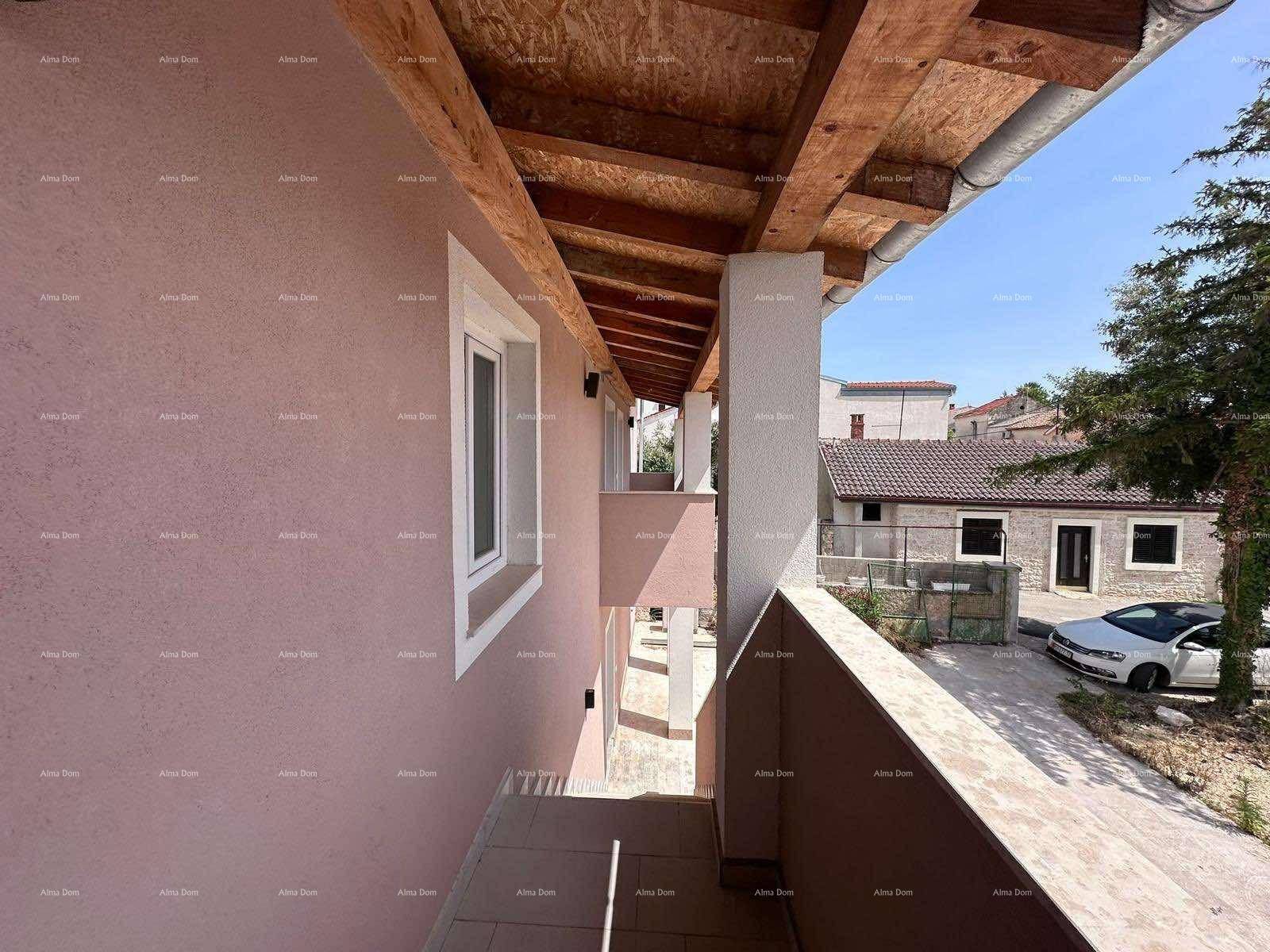 Blick von einem Balkon auf den Eingangsbereich des Gebäudes und die gepflasterte Zufahrt.