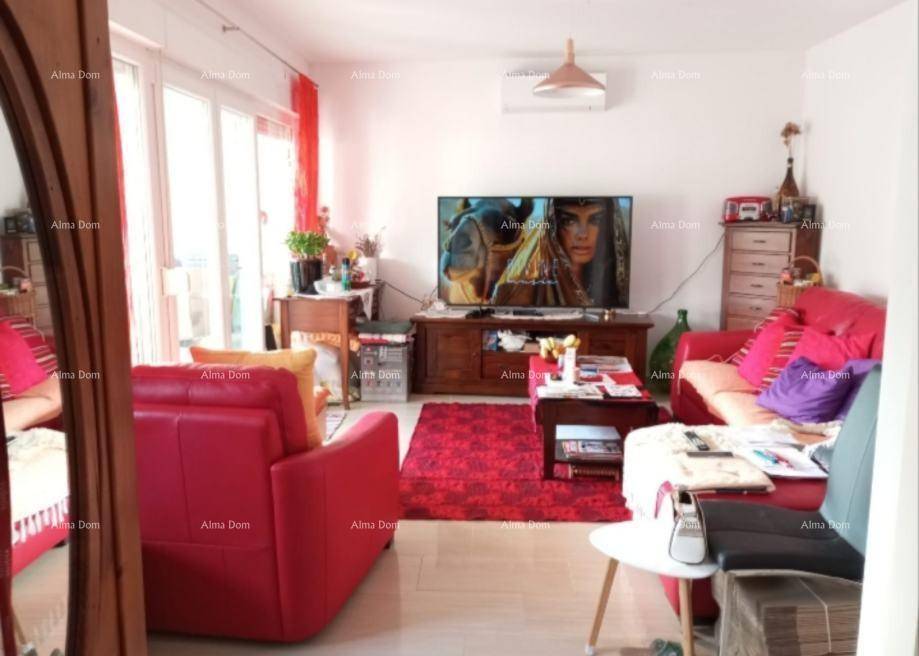 Helles Wohnzimmer mit roten Sofas, Fernseher und Zugang zu einem Balkon oder einer Terrasse.