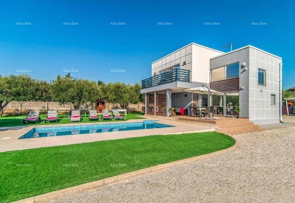 Gesamtansicht des modernen Hauses mit Poolbereich, Kunstrasen und Kiesauffahrt an einem sonnigen Tag.