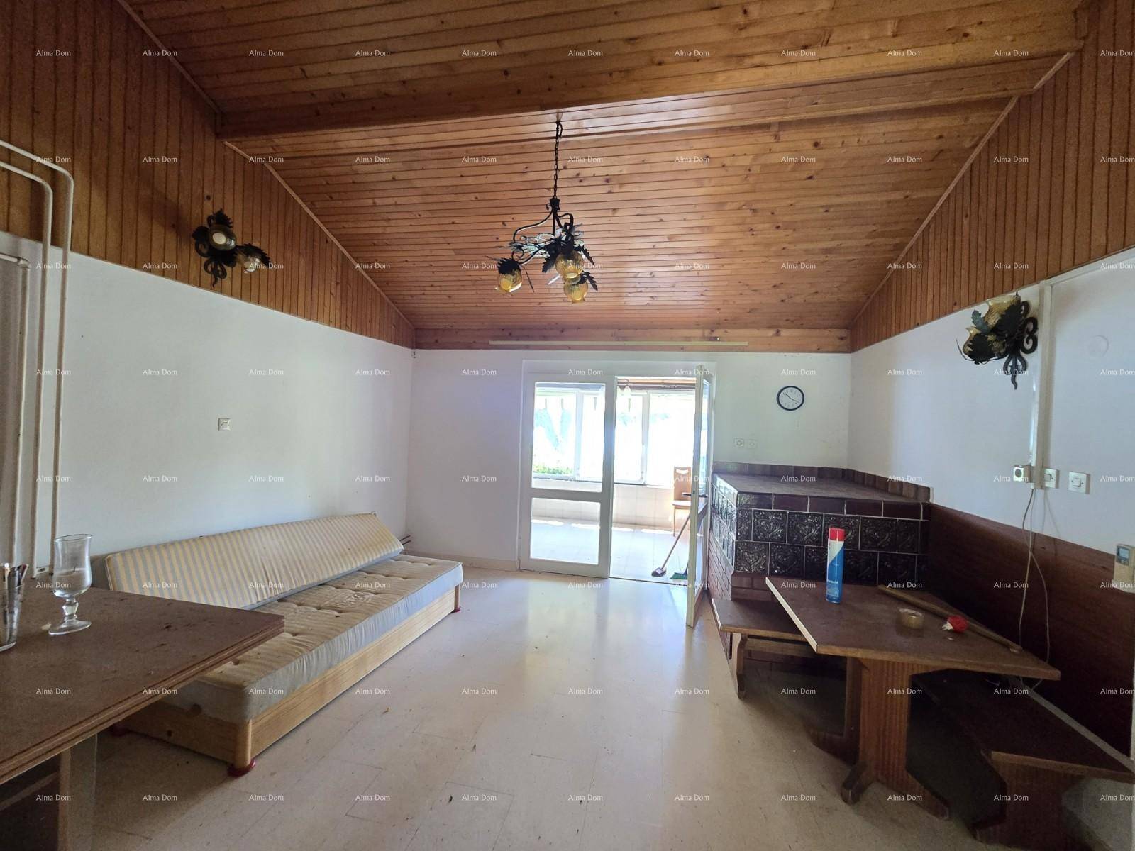 Gemütliches Wohnzimmer mit Holzdach, Sofa und traditionellem Kachelofen, strahlt Wärme aus.