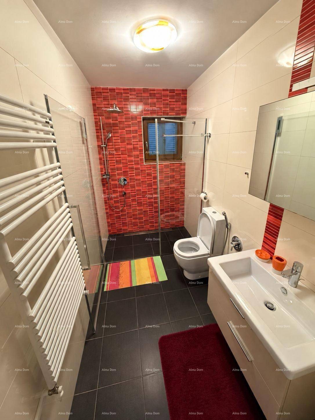 Modernes Badezimmer mit begehbarer Dusche, WC, Waschtisch und roter Akzentwand.