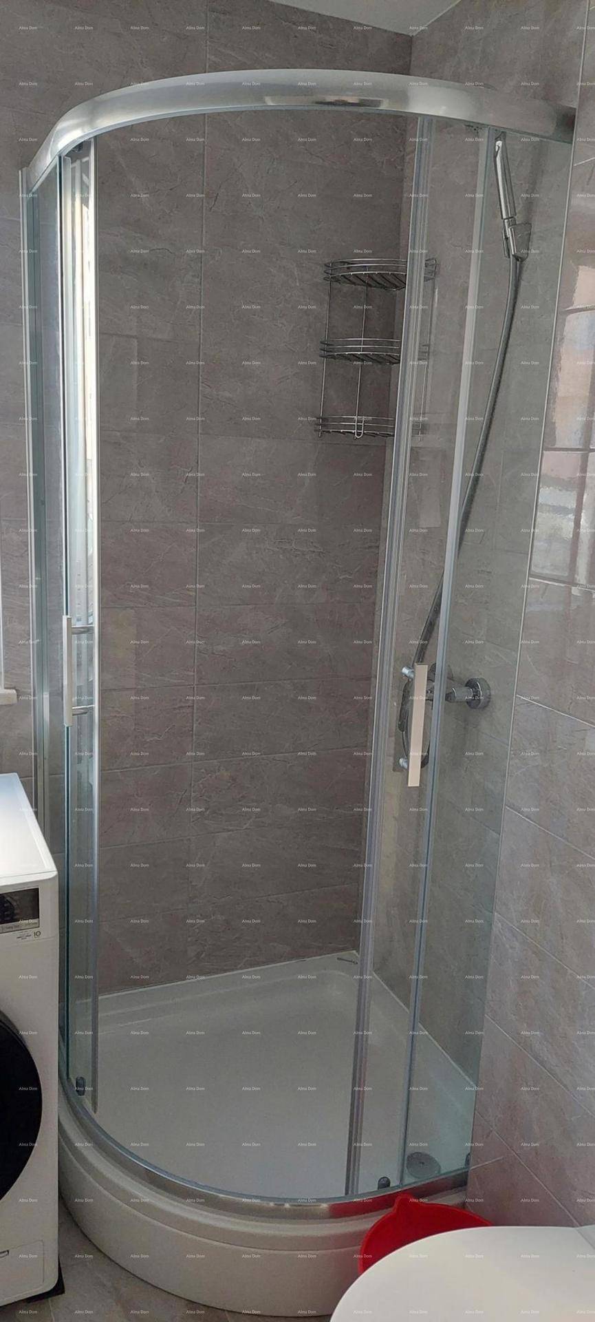Duschkabine mit Glastüren und grauen Fliesen im modernen Badezimmer.