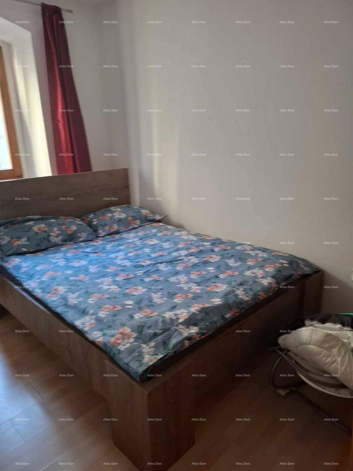 Schlafzimmer mit Doppelbett, hellem Laminatboden und einem Fenster mit roten Vorhängen.