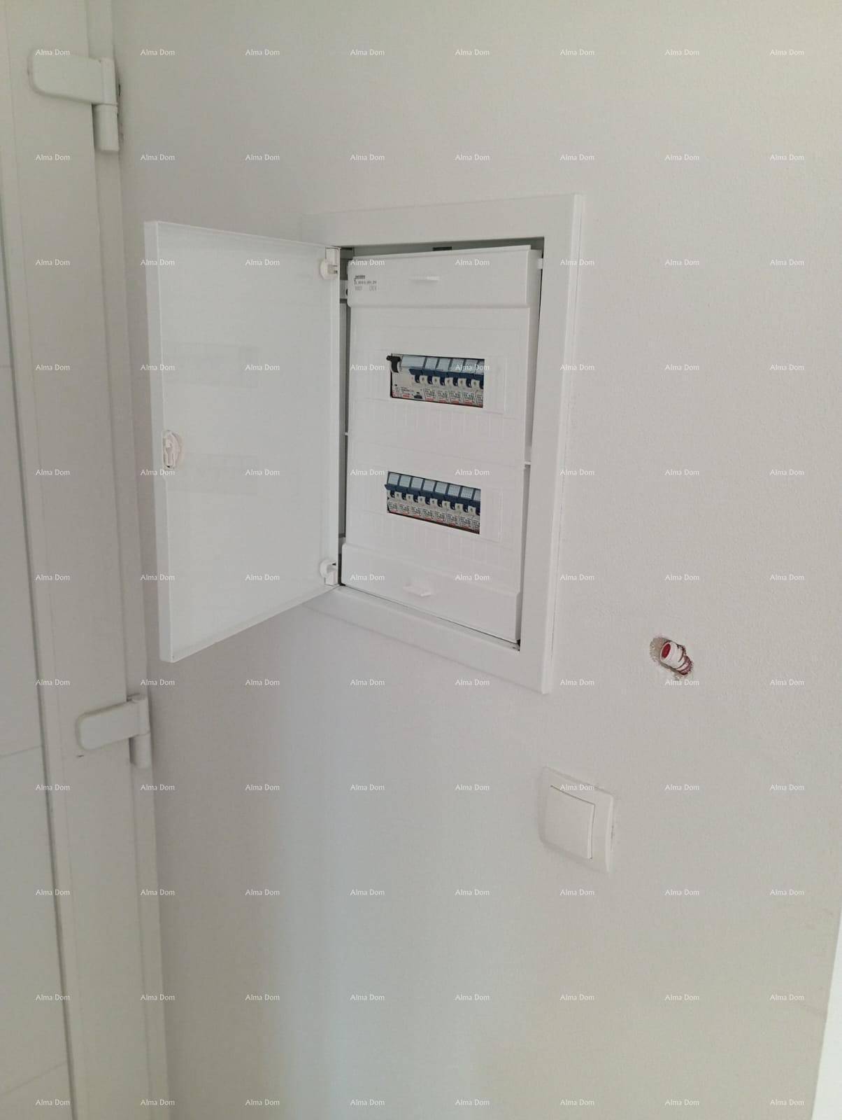 Offener Sicherungskasten an einer weißen Wand in einem unfertigen Innenraum.