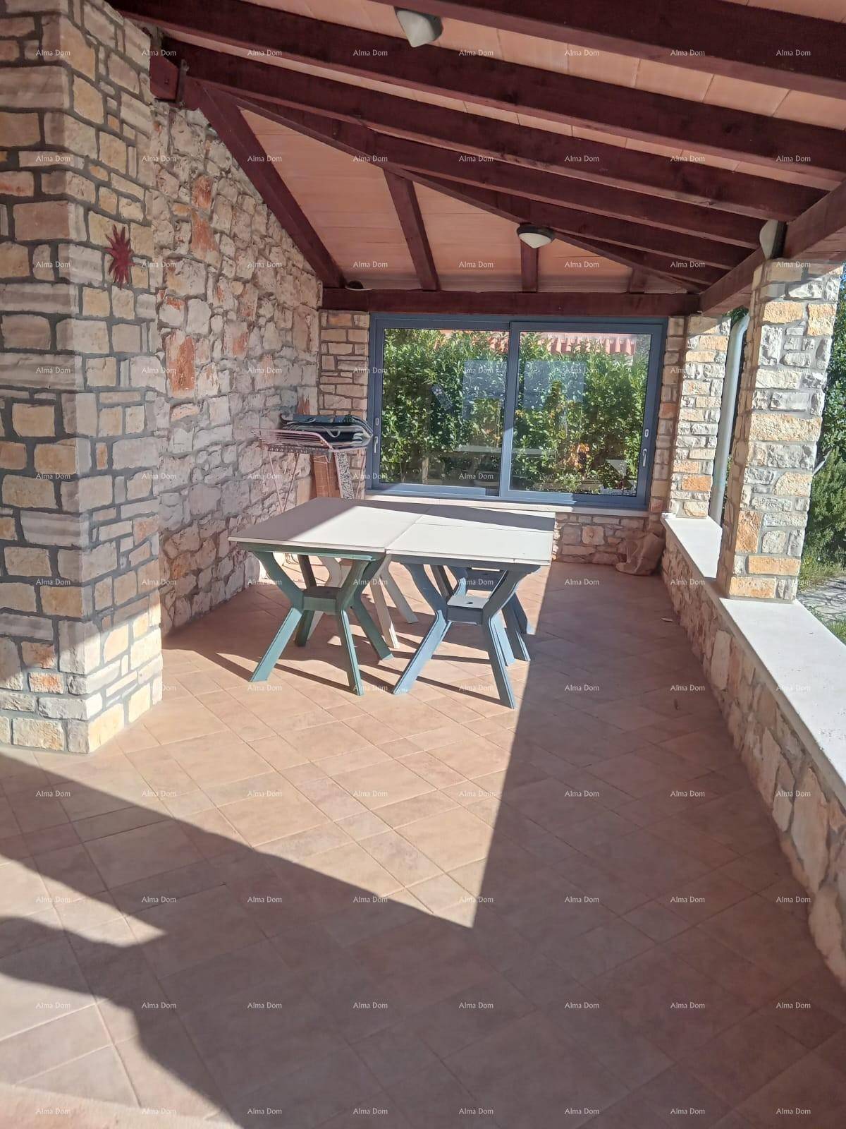 Überdachte Terrasse mit Steinsäulen, Holzbalkendecke und Esstisch im Freien.