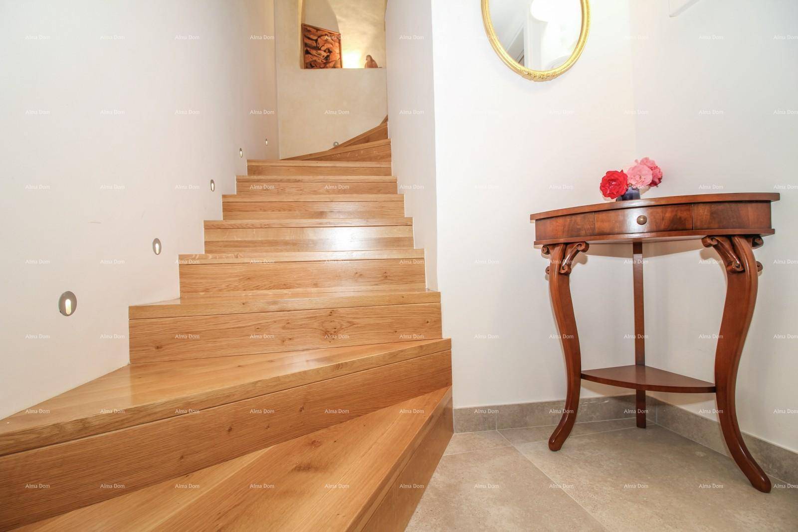 Detailansicht der geschwungenen Holztreppe mit Wandbeleuchtung und einem antiken Konsolentisch im Flur.