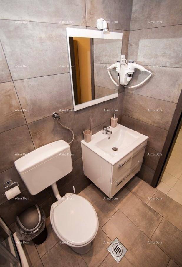 Helles Badezimmer mit Waschbecken, Toilette, Spiegel und grauen Wand- und Bodenfliesen.