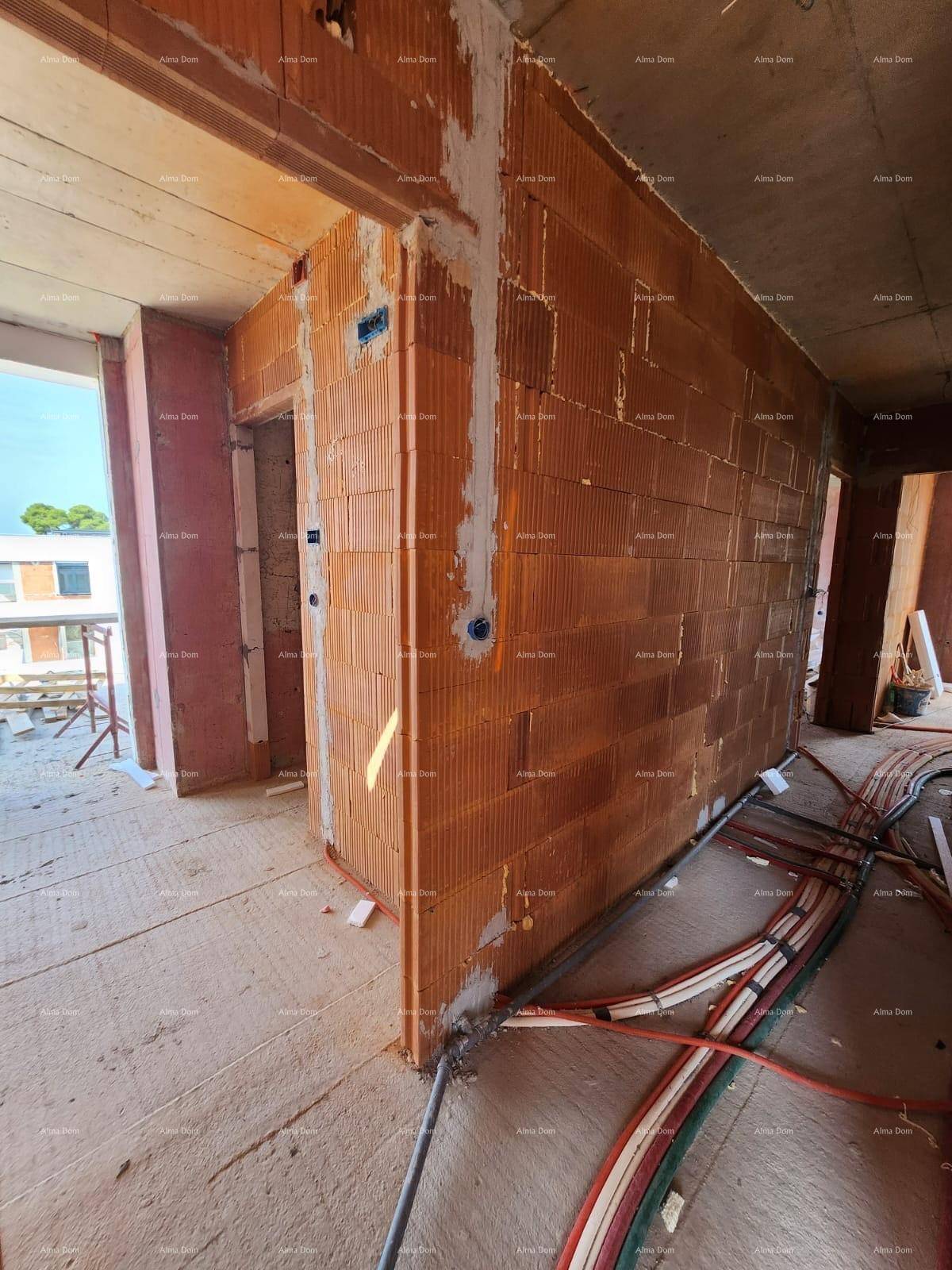 Ecke eines Raumes im Rohbau mit Ziegelwänden und sichtbaren Elektroinstallationen auf dem Boden.