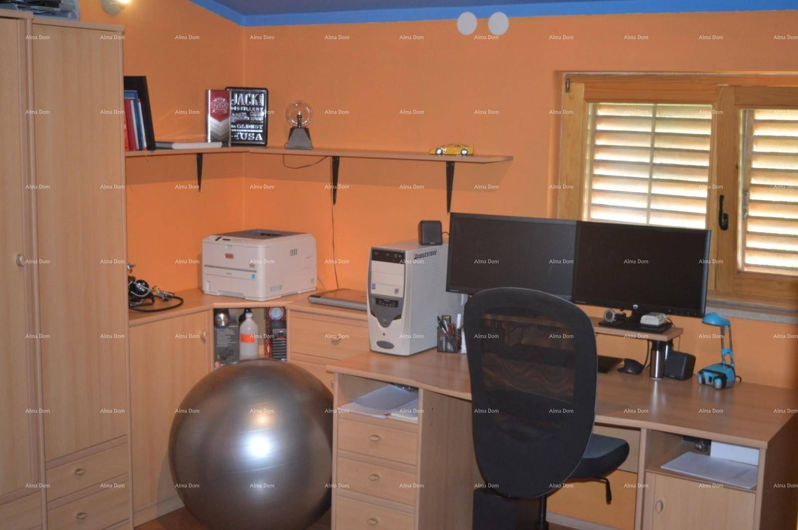 Arbeitszimmer mit Schreibtisch, Computer und Regalen, gestaltet in warmen Orangetönen.