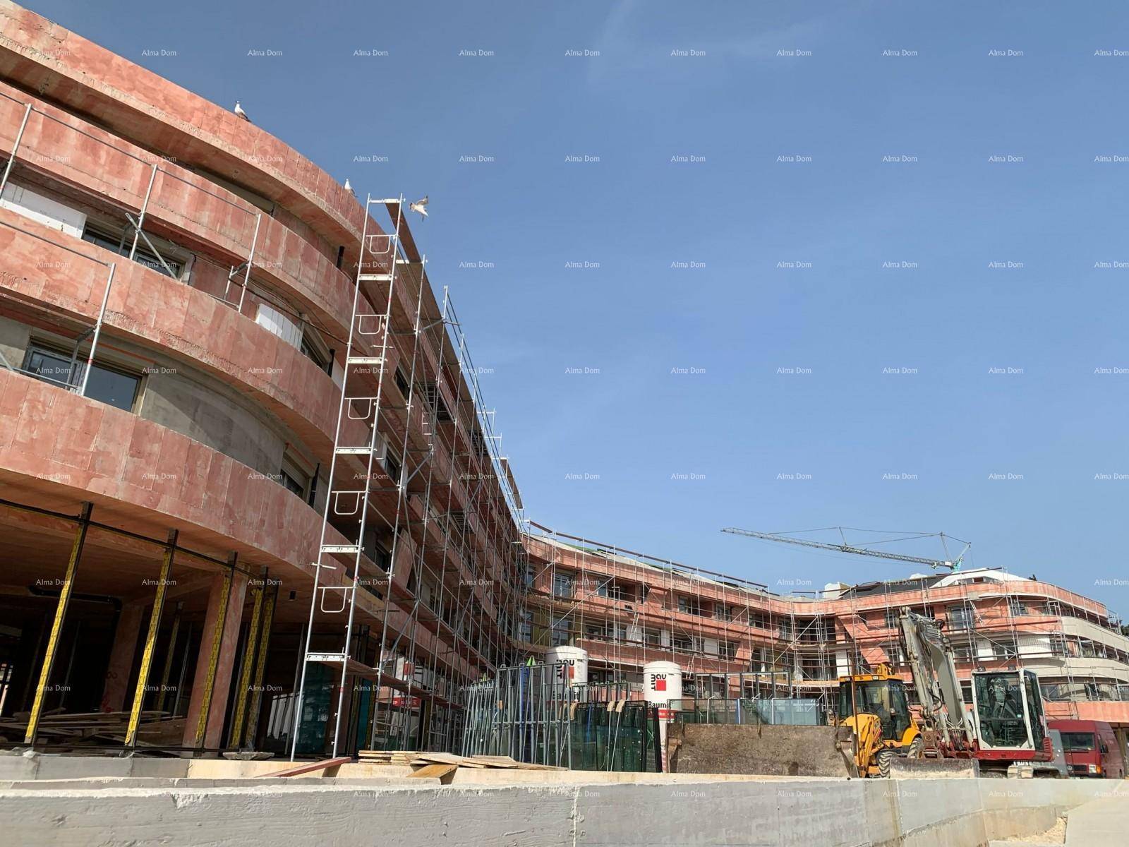Ansicht der geschwungenen Fassade der Wohnanlage im Bau mit Gerüst und Baukran im Hintergrund.