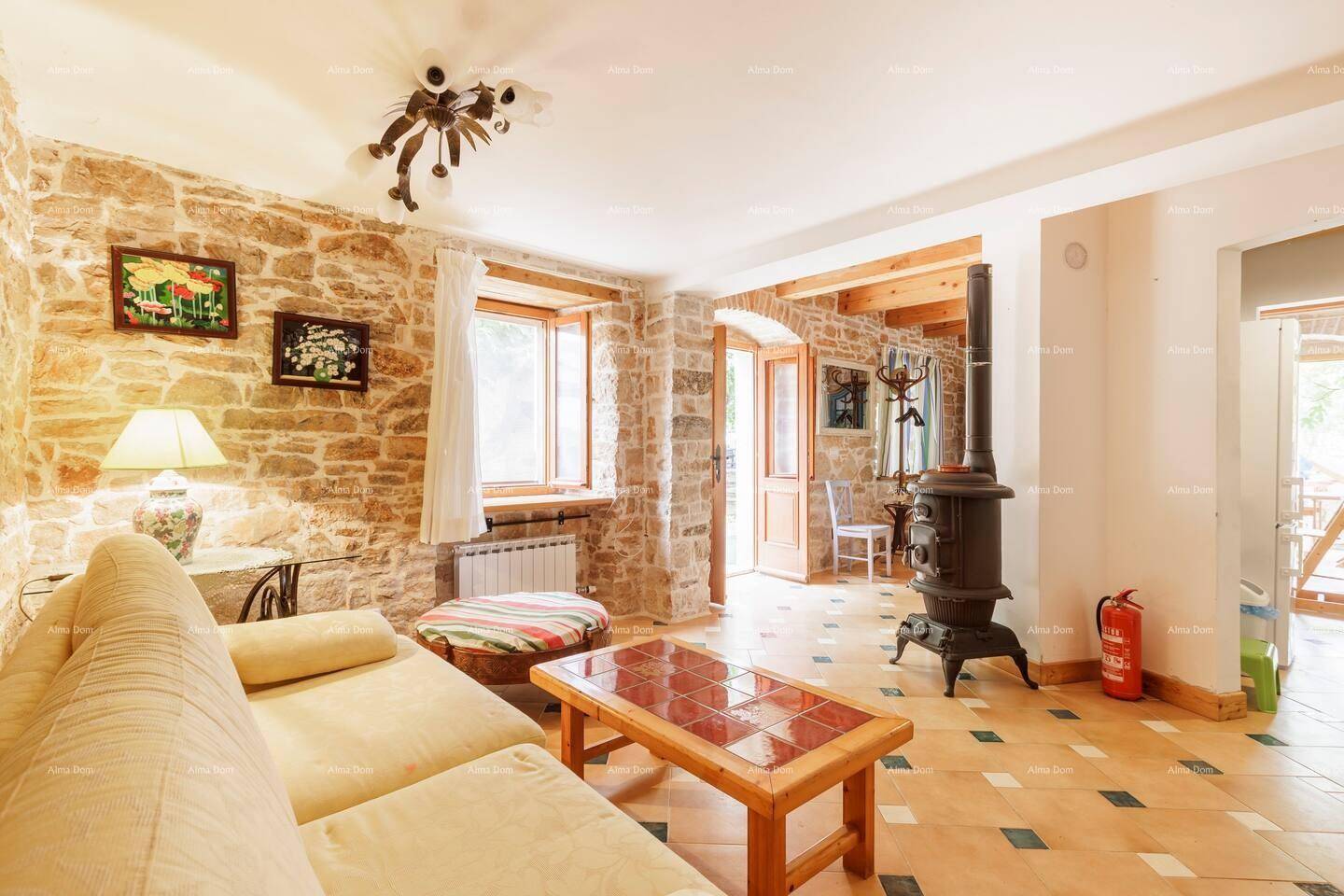 Gemütliches Wohnzimmer mit Steinwänden, Fliesenboden und einem traditionellen Holzofen.