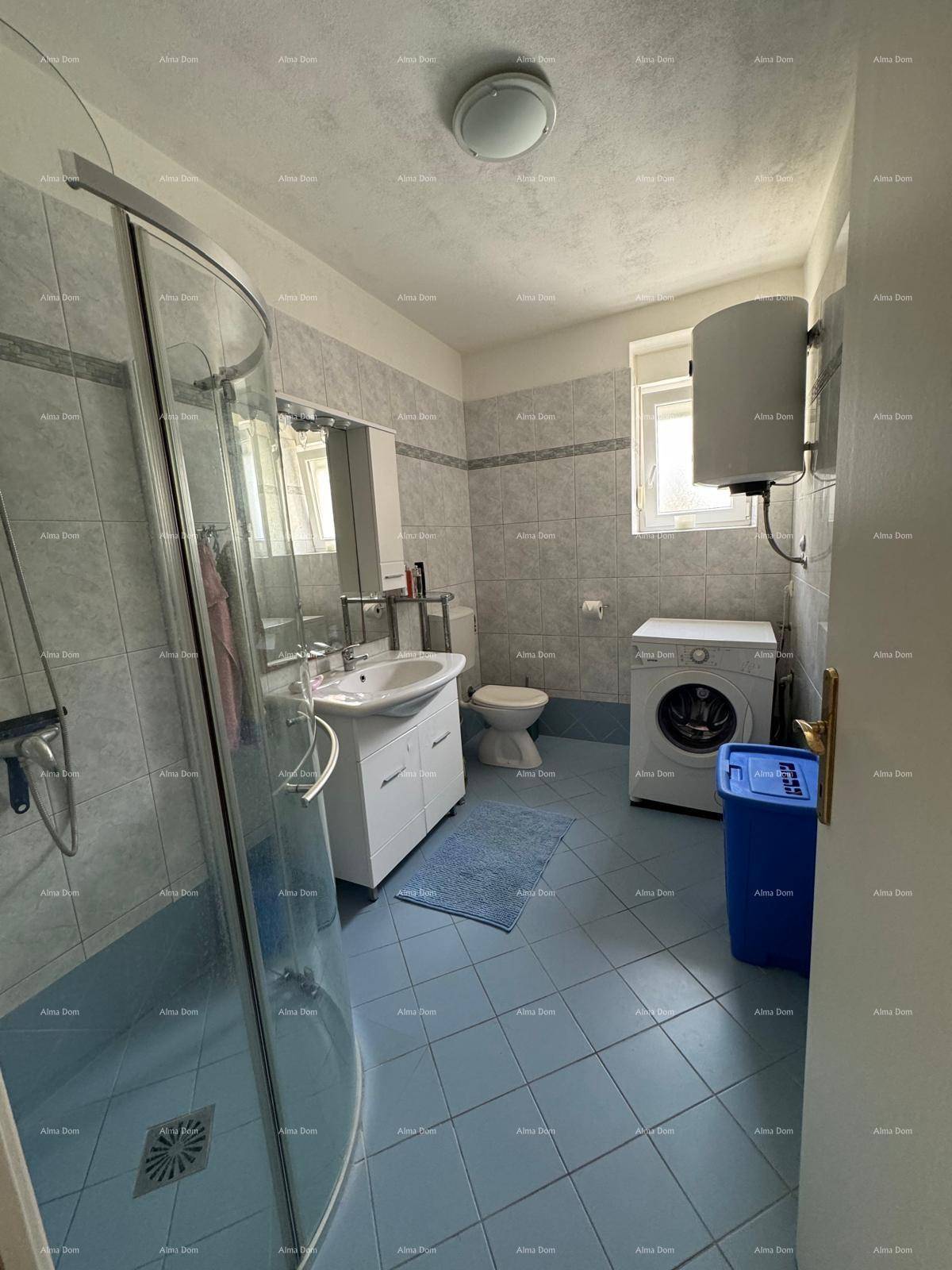 Badezimmer mit blauen Bodenfliesen, Duschkabine, Waschmaschine und Fenster für Tageslicht.