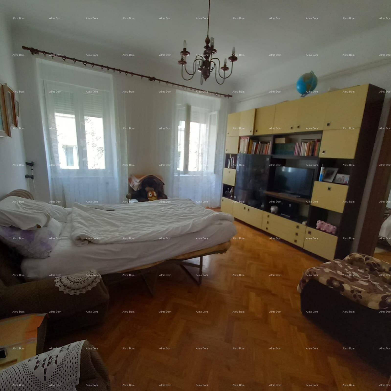 Helles Schlafzimmer mit Parkettboden, großem Wandschrank und zwei Fenstern.