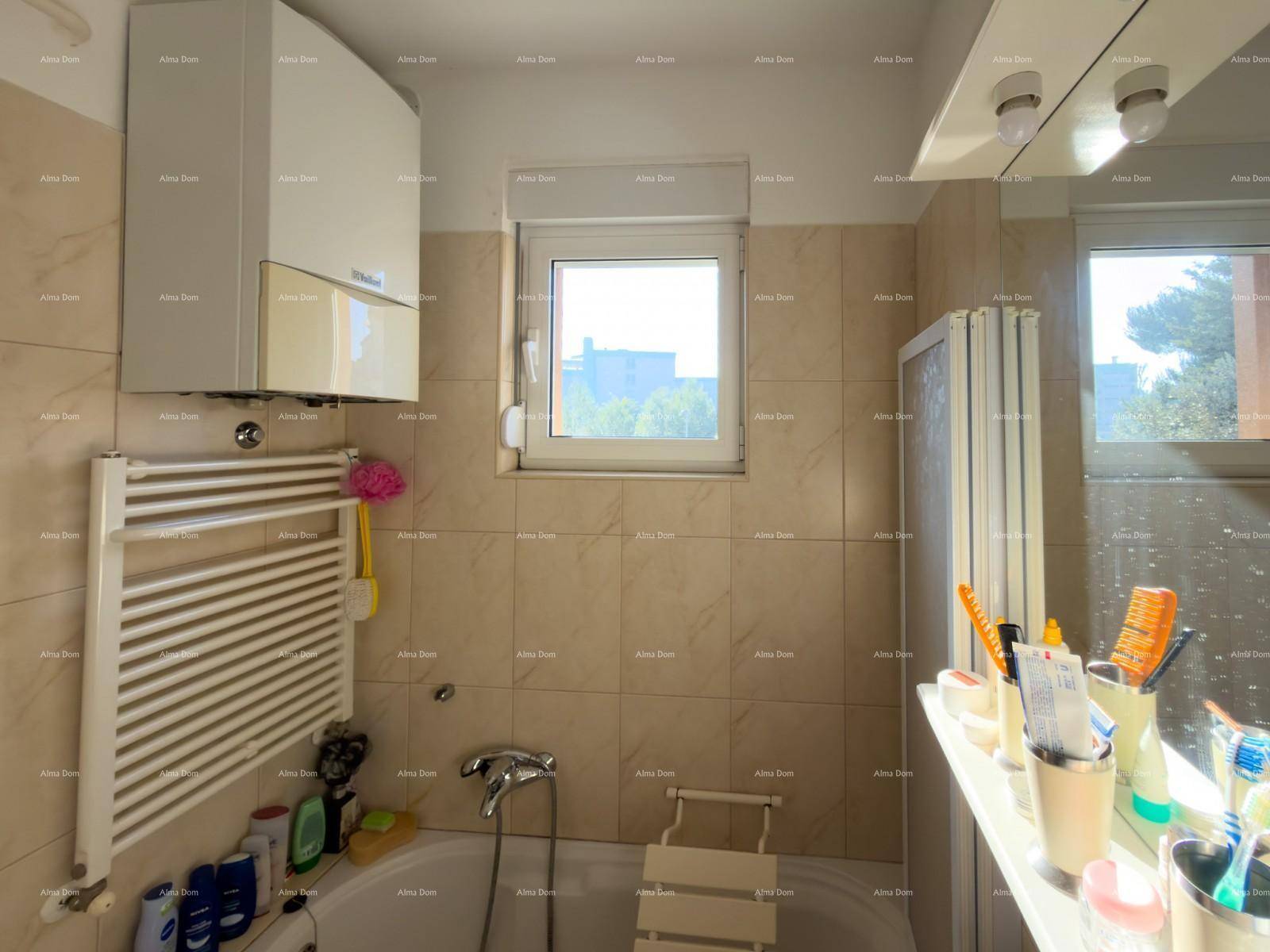 Badezimmer mit Badewanne, beheiztem Handtuchhalter und zwei Fenstern für Tageslicht.