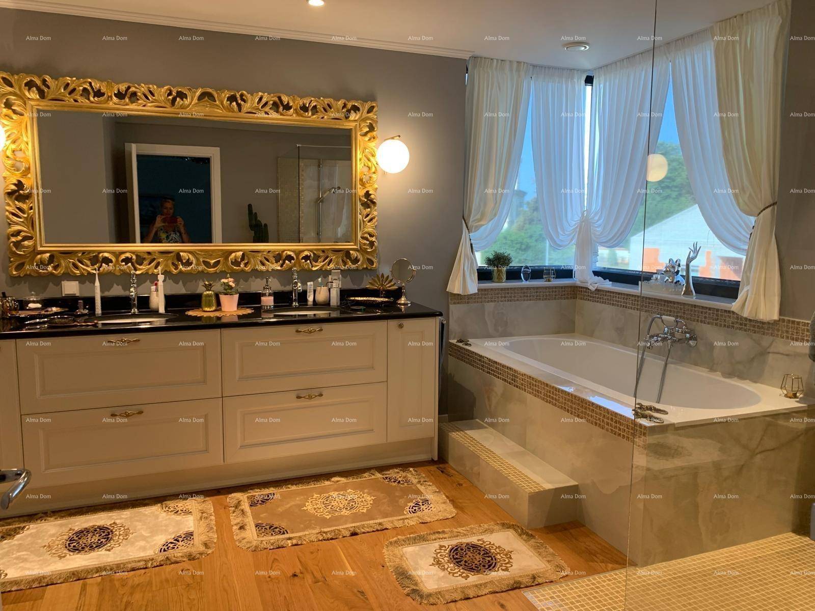Luxuriöses Badezimmer mit großer Badewanne, Doppelwaschbecken und vergoldetem Spiegel.