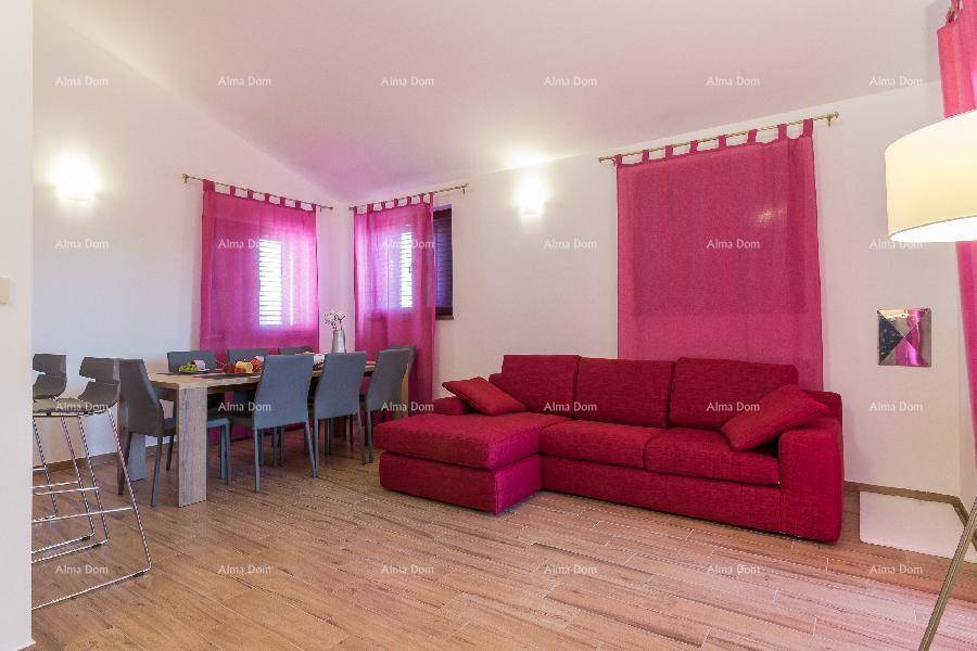 Geräumiges Wohnzimmer mit großem roten Sofa und Essbereich im Hintergrund.