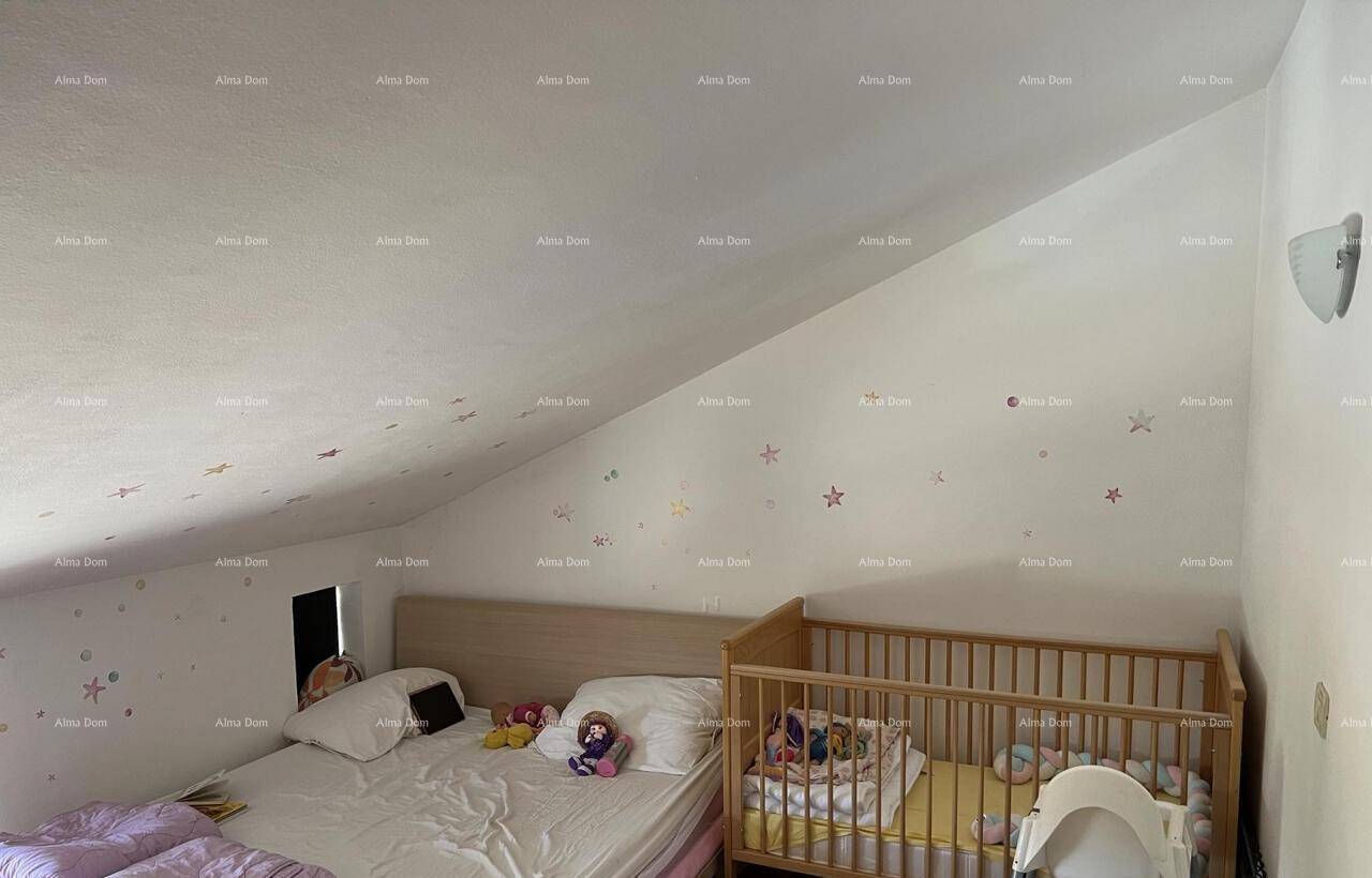 Dachgeschoss-Schlafzimmer mit schrägen Wänden, einem Doppelbett und einem Babybett, dekoriert mit Sternen.