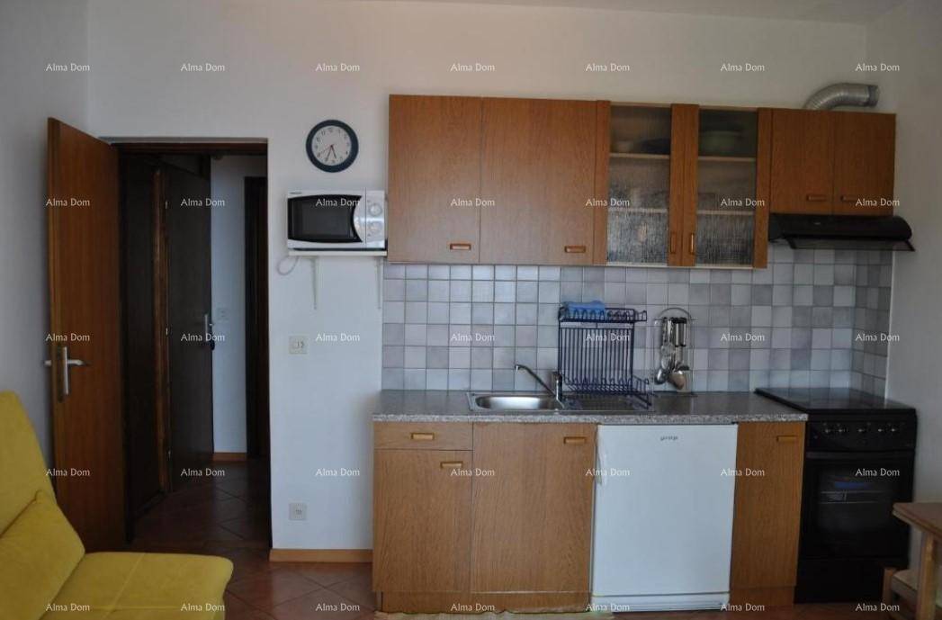 Kleine Küche mit Holzschränken, Fliesenrückwand und grundlegenden Küchengeräten.