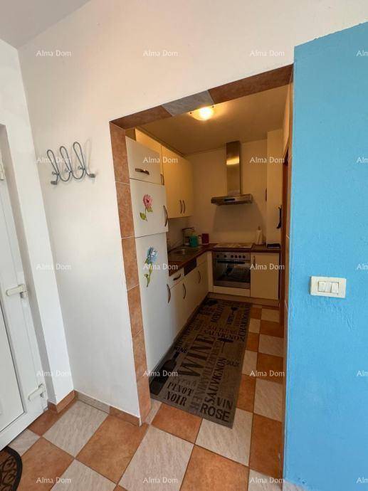 Kleine, funktionale Küche mit weißen Schränken, Herd und Kühlschrank in einem Durchgangsbereich.