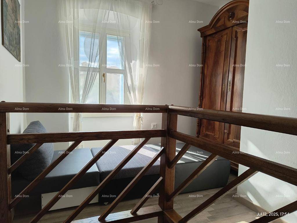 Gemütlicher Wohnbereich im Obergeschoss mit Sofa und Holzgeländer, hell durch das Fenster.