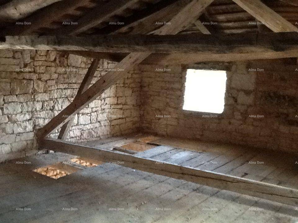 Dachbodenraum mit freiliegenden Holzbalken, Steinwänden und alten Holzdielen.