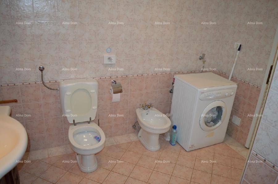 Badezimmer mit WC, Bidet und Waschmaschine, ausgestattet mit rosa-beigen Fliesen.