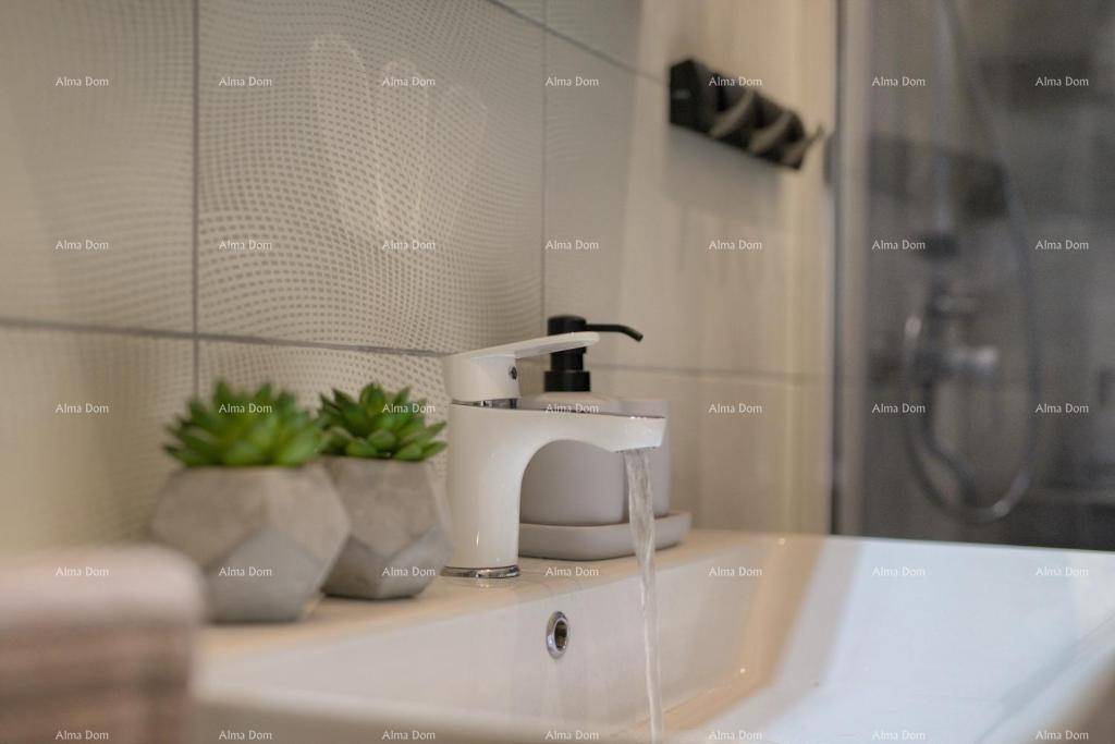 Nahaufnahme eines modernen Waschbeckens mit stilvollem Wasserhahn und kleinen Pflanzen.
