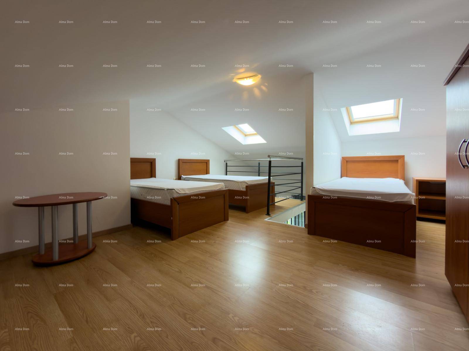 Geräumiges Schlafzimmer im Dachgeschoss mit mehreren Betten, Holzfußboden und Dachfenstern.