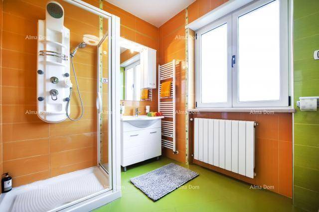 Farbiges Badezimmer in Orange und Grün mit Duschkabine, Fenster und Handtuchheizkörper.