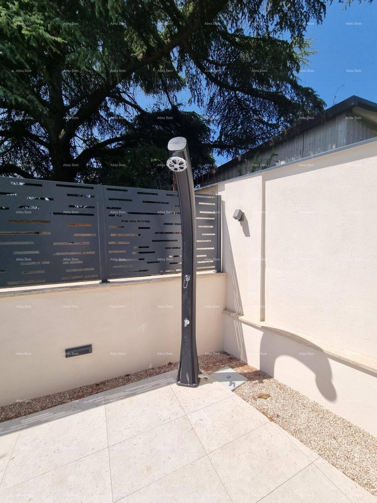 Moderne Außendusche auf der gefliesten Terrasse neben der Villa.