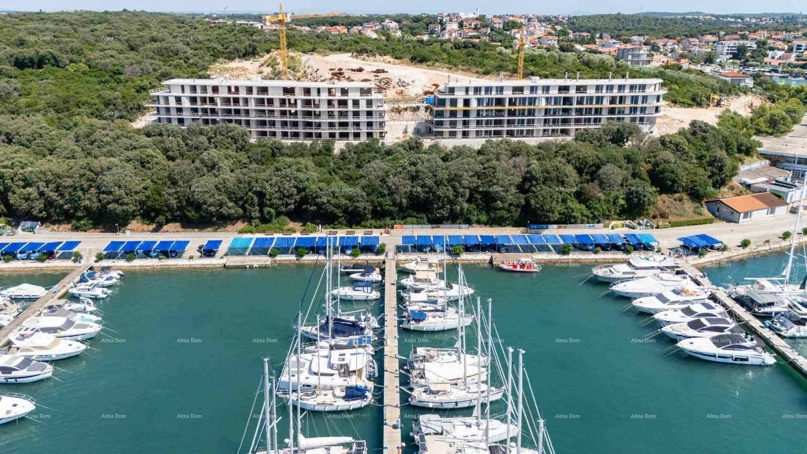 Luftaufnahme eines Yachthafens mit zahlreichen Booten und einer Baustelle im Hintergrund.