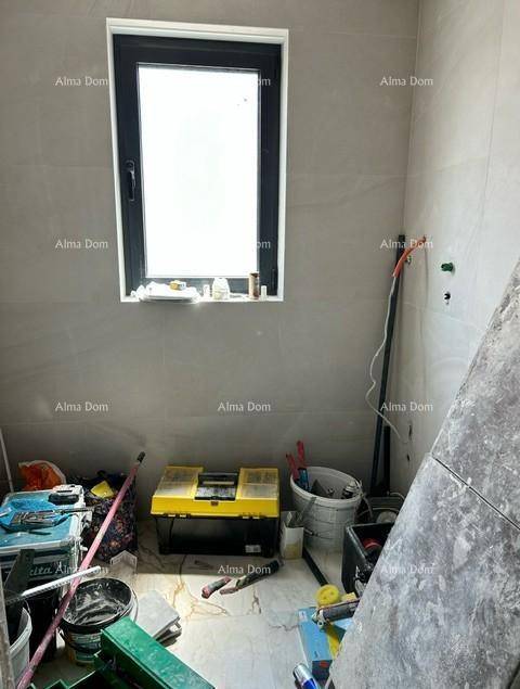 Badezimmer im Bau mit Fenster, hellen Fliesen und Baumaterialien auf dem Boden.