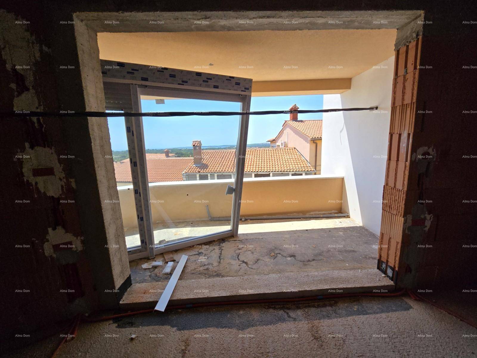 Blick aus dem Rohbau durch eine große Fensteröffnung auf die umliegenden Dächer und die weite Landschaft.
