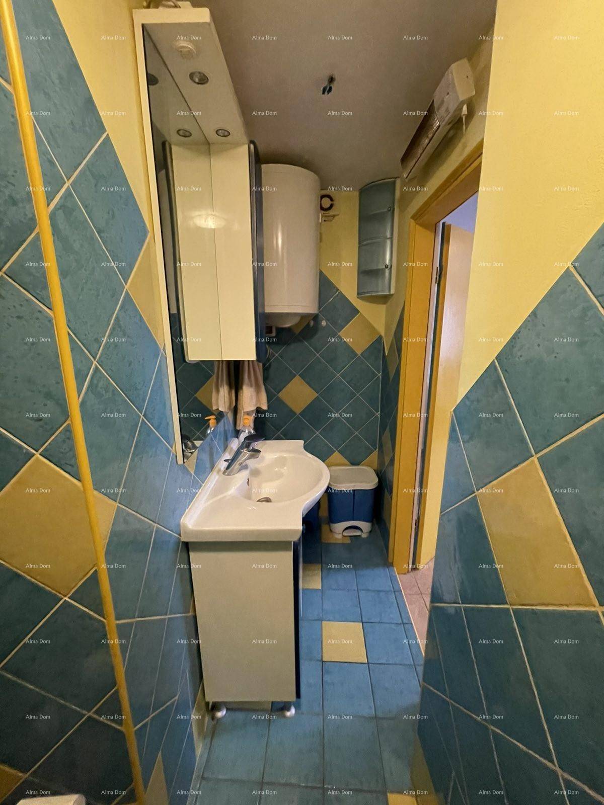 Waschbecken mit Spiegelschrank und Warmwasserbereiter in einem farbenfroh gefliesten Badezimmer.