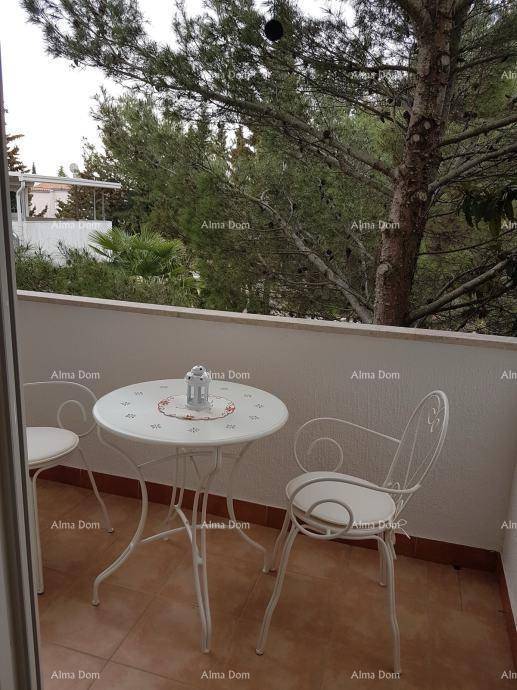 Gemütlicher Balkon mit weißem Metalltisch und Stühlen, umgeben von üppigem Grün.
