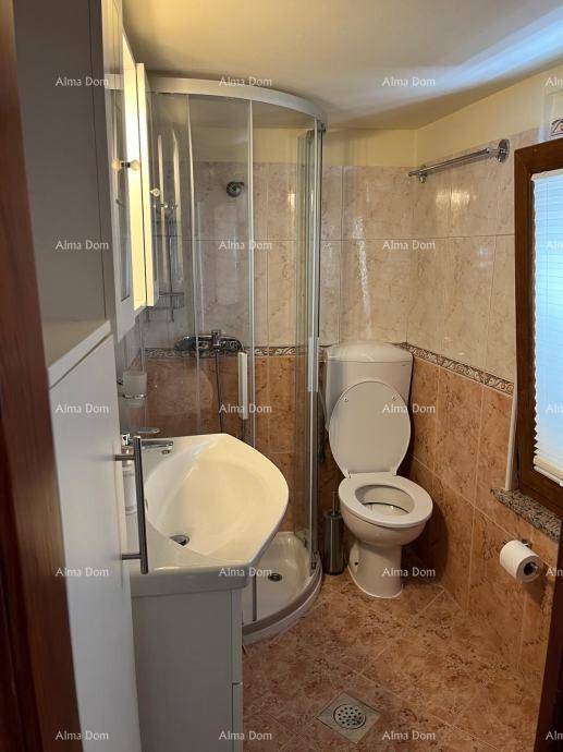 Badezimmer mit Duschkabine, WC, Waschbecken und Fenster, ausgestattet mit Fliesen.