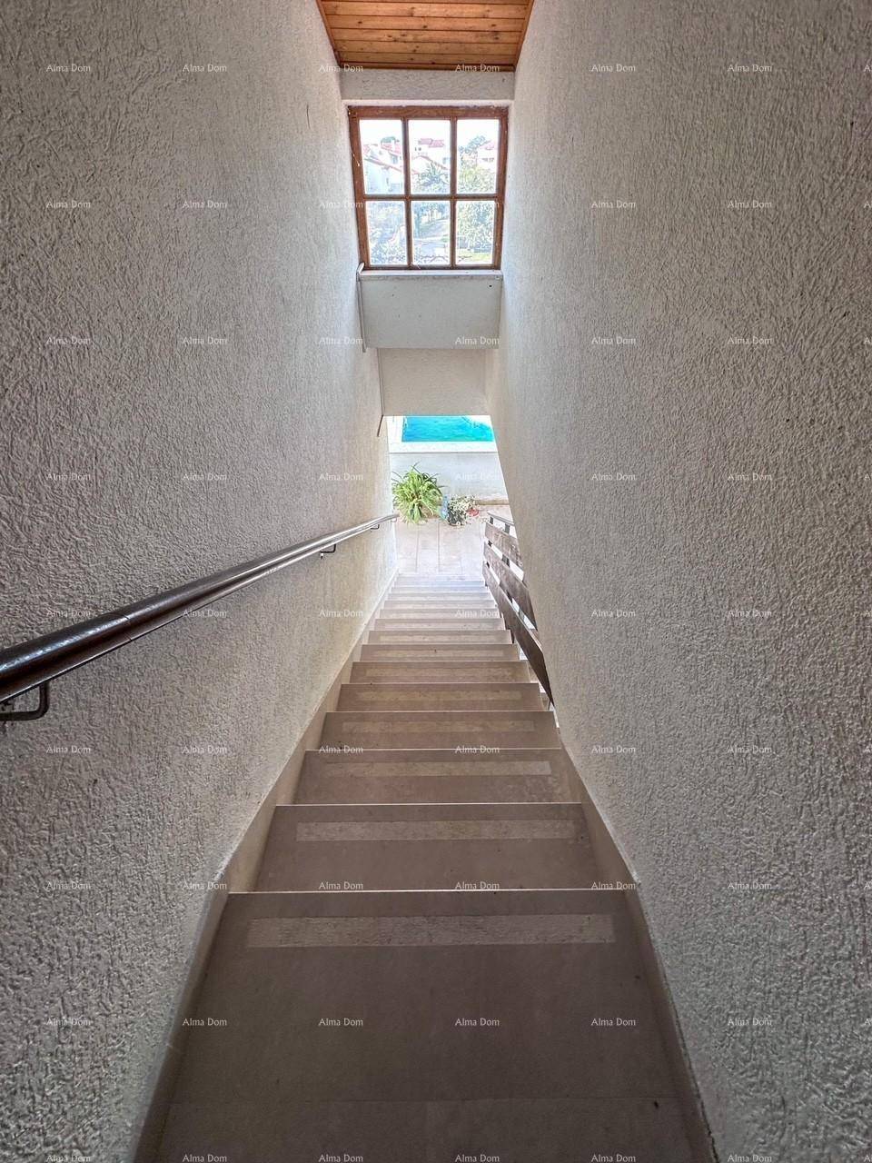 Treppenhaus mit Handlauf und einem Fenster am oberen Ende, das Tageslicht hereinlässt.