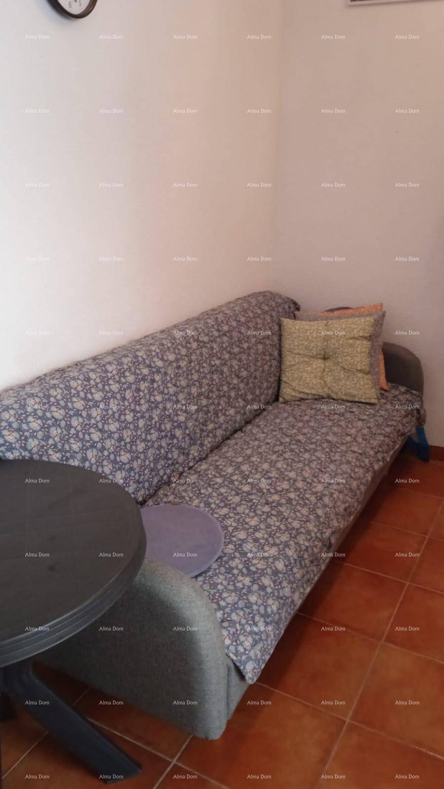 Schlafsofa mit floralem Bezug und kleinem runden Tisch in einem einfachen Wohnbereich.