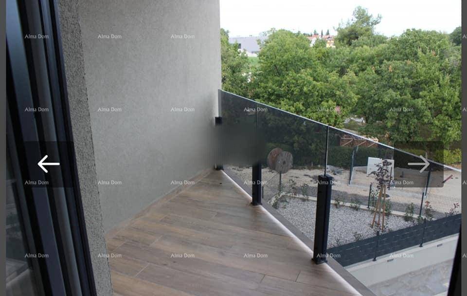 Moderner Balkon mit Glasgeländer und Holzoptik-Fliesenboden, umgeben von grünen Bäumen.