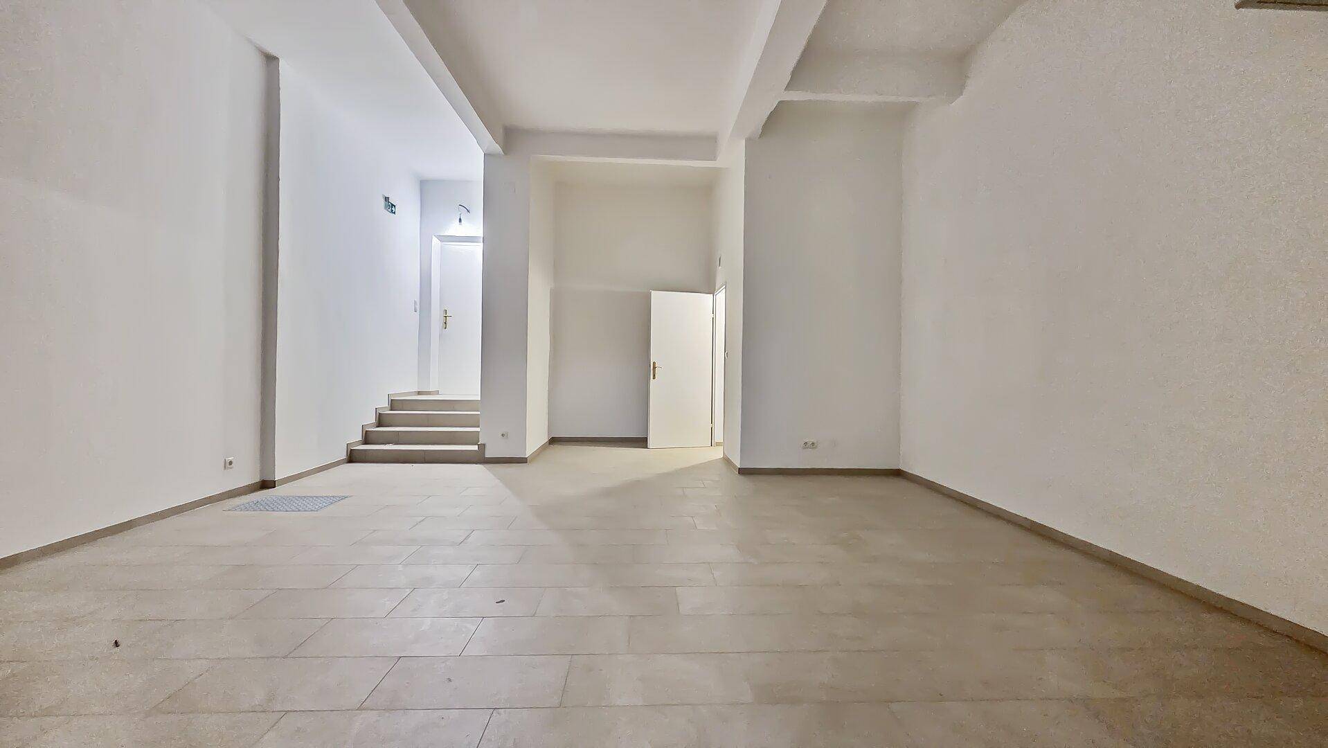 Großer, leerer Raum mit hellen Fliesen und hohen Decken, ideal für flexible Nutzungsmöglichkeiten.