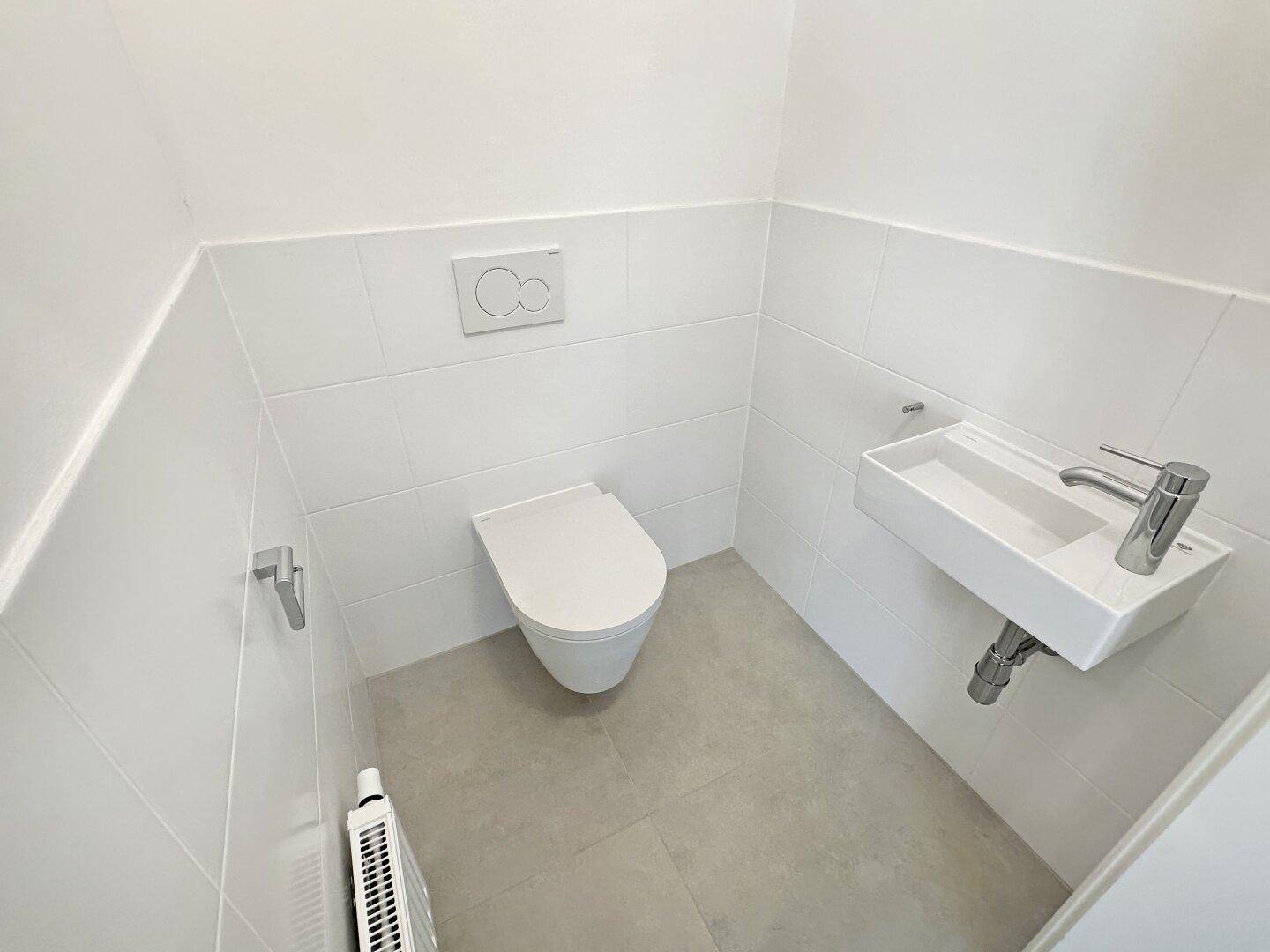 Kleines, modernes Gäste-WC mit wandhängender Toilette und einem kompakten Handwaschbecken.