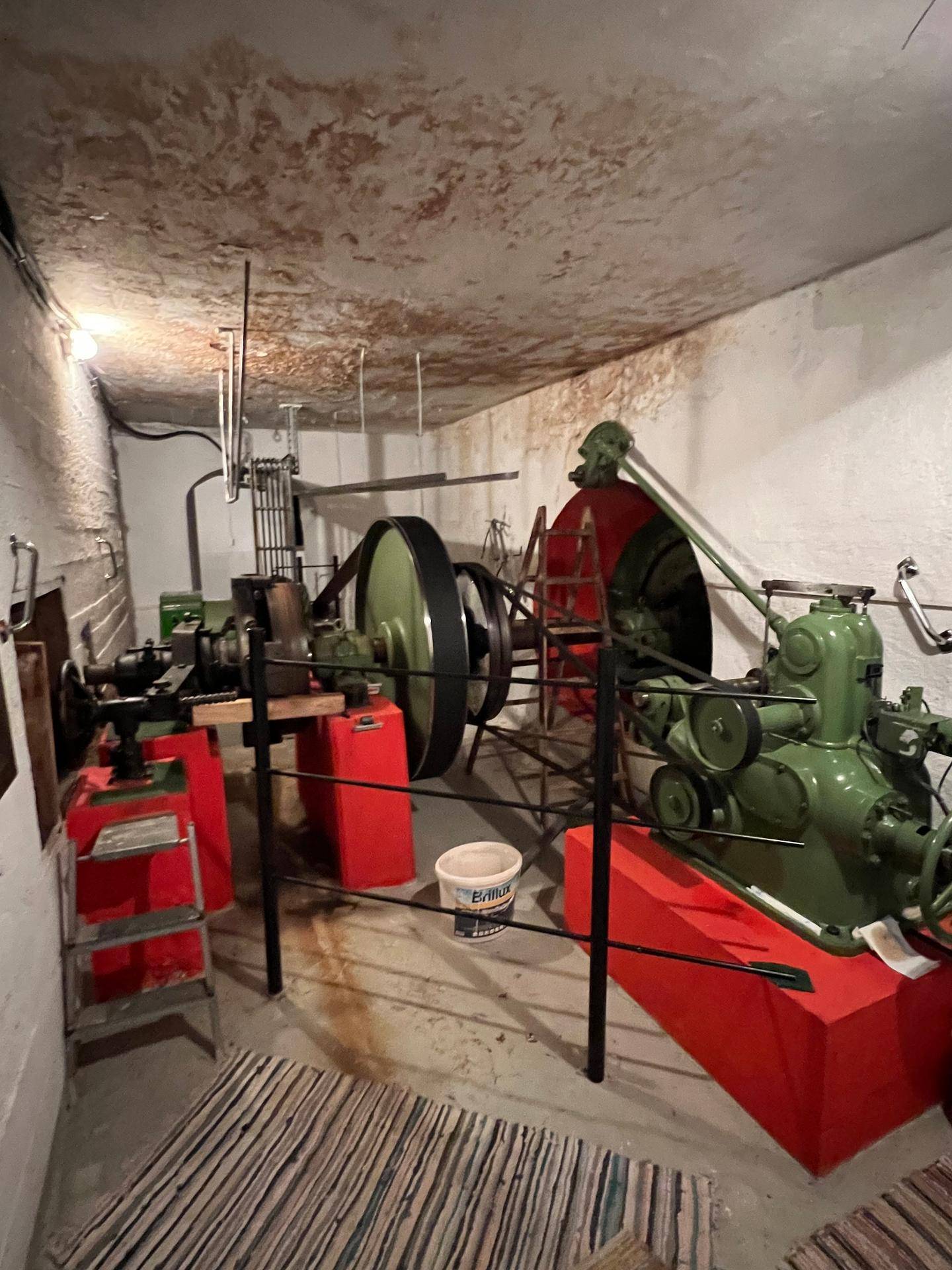 Maschinenraum mit großen grünen Industrieanlagen und roten Sockeln, gut beleuchtet.