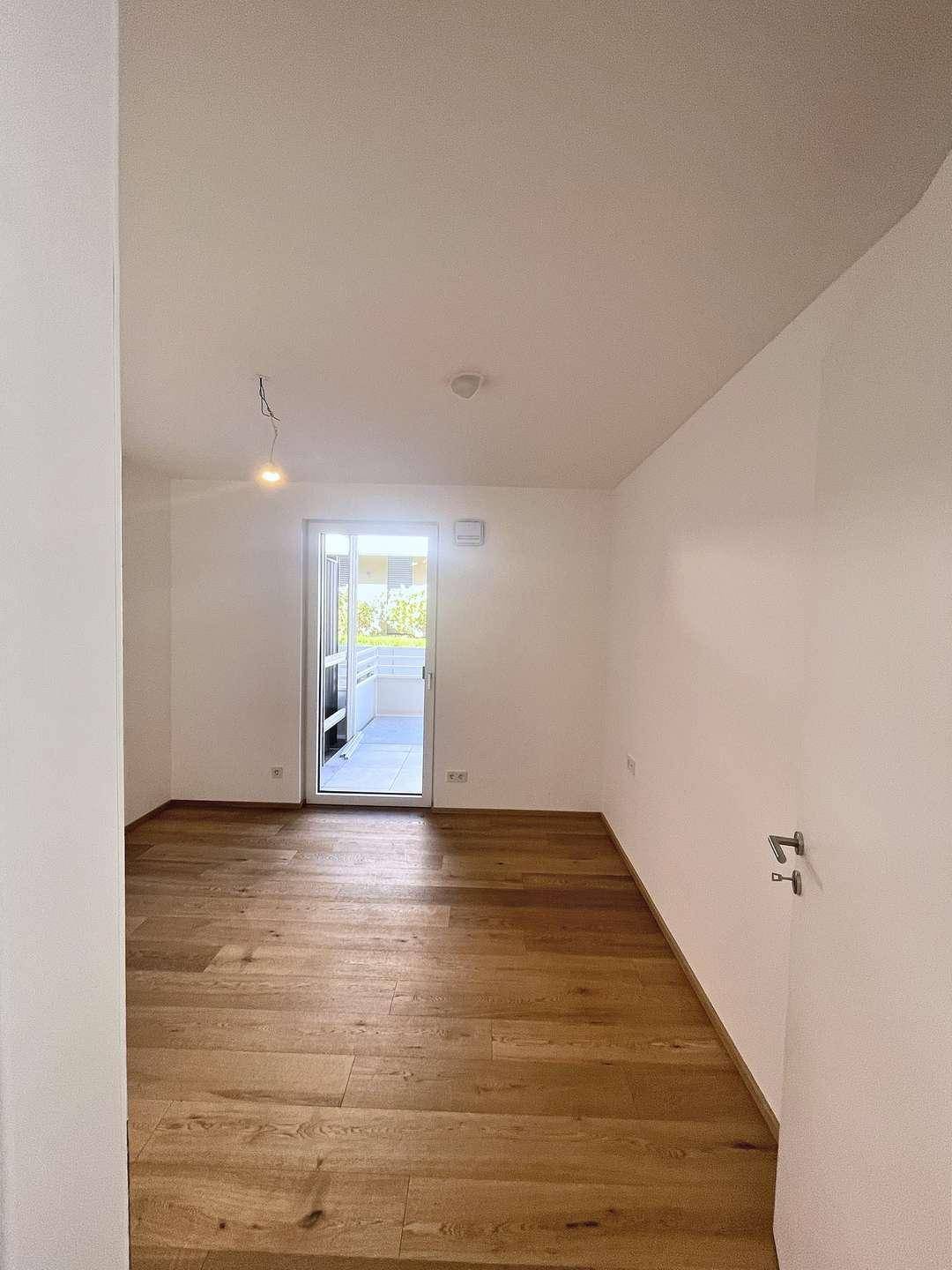 Heller Wohnraum mit Holzboden und Zugang zu einem Außenbereich, ideal für Entspannung.