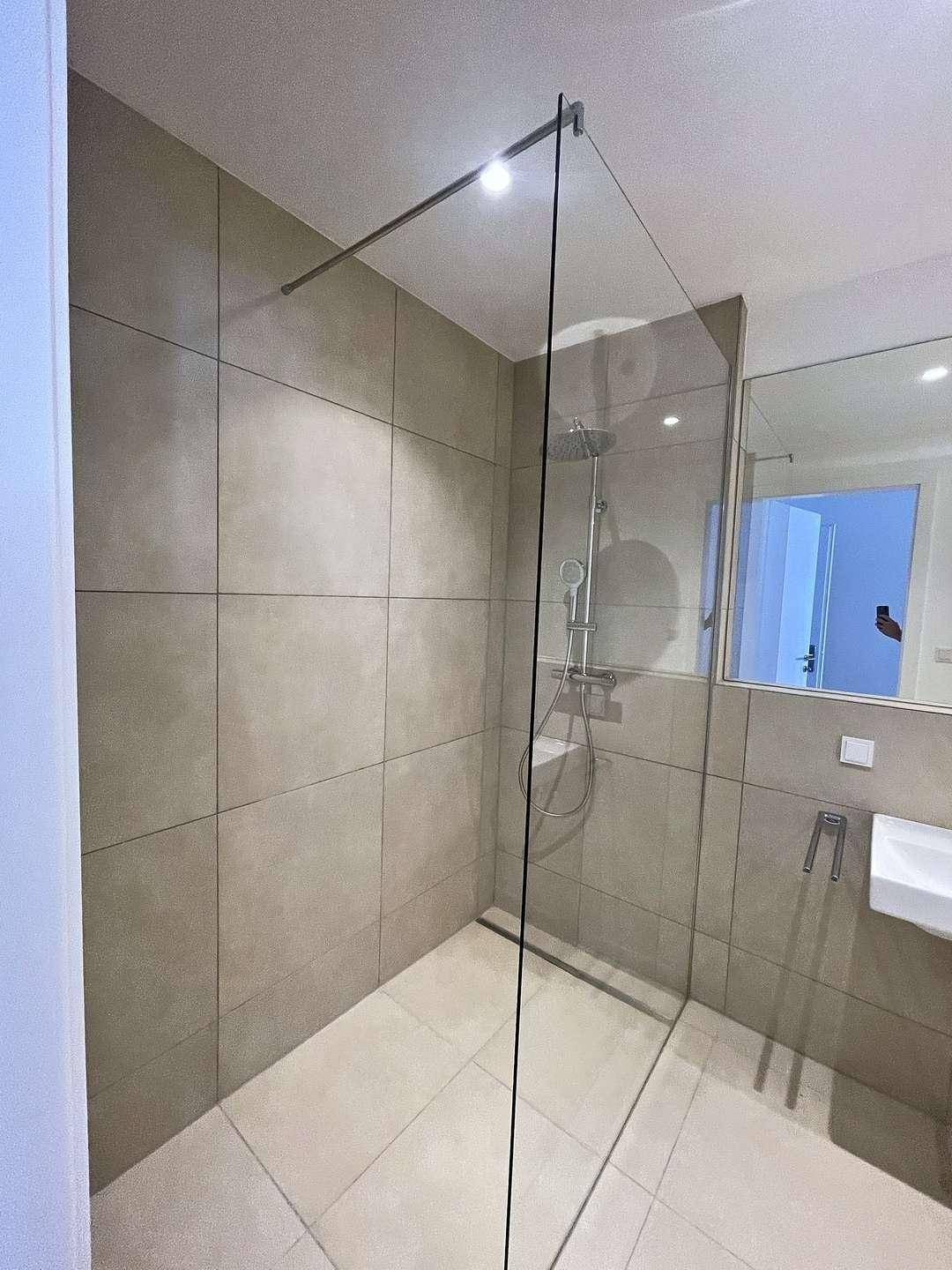 Modernes Badezimmer mit begehbarer Dusche, Regendusche und großen Fliesen.