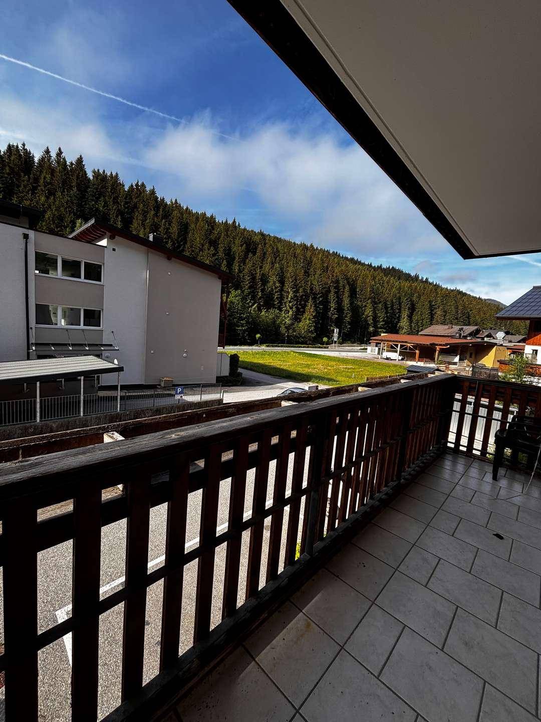 Balkon mit Holzbalkonbrüstung bietet einen weiten Blick auf die umliegenden Berge und Wälder.
