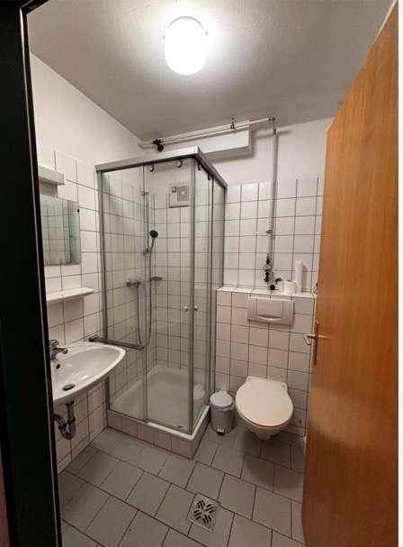 Funktionales Badezimmer mit Duschkabine, WC und Waschbecken, komplett gefliest.